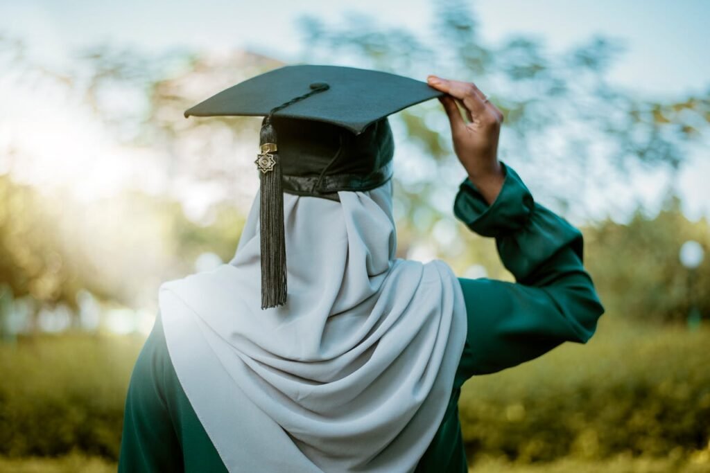 A hijabi woman celebrates graduation outdoors with an academic cap under the summer sky in Maldives.