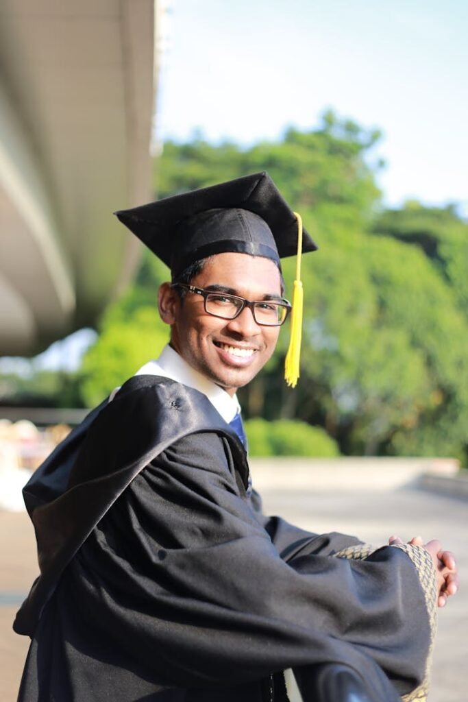 Happy graduate in cap and gown, Cyberjaya, celebrating outdoor achievement.